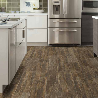 Contemporary kitchen featuring distressed dark brown wood-look tile flooring, white cabinetry, stainless steel appliances, and a light-colored kitchen island with a rustic yet modern aesthetic.